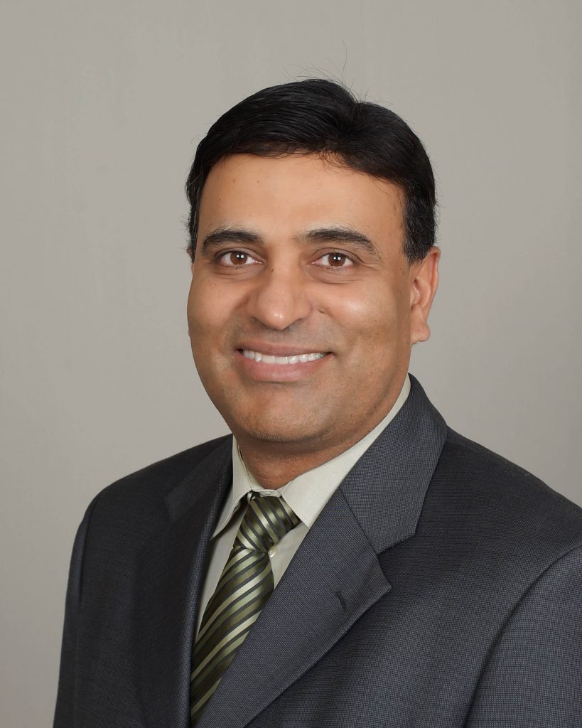 A man in a suit and tie smiling for the camera.